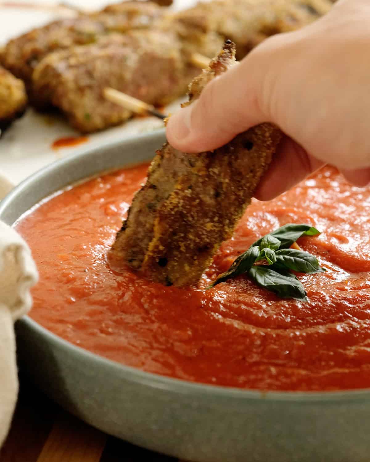 Dipping grilled beef spiedini in marinara sauce.