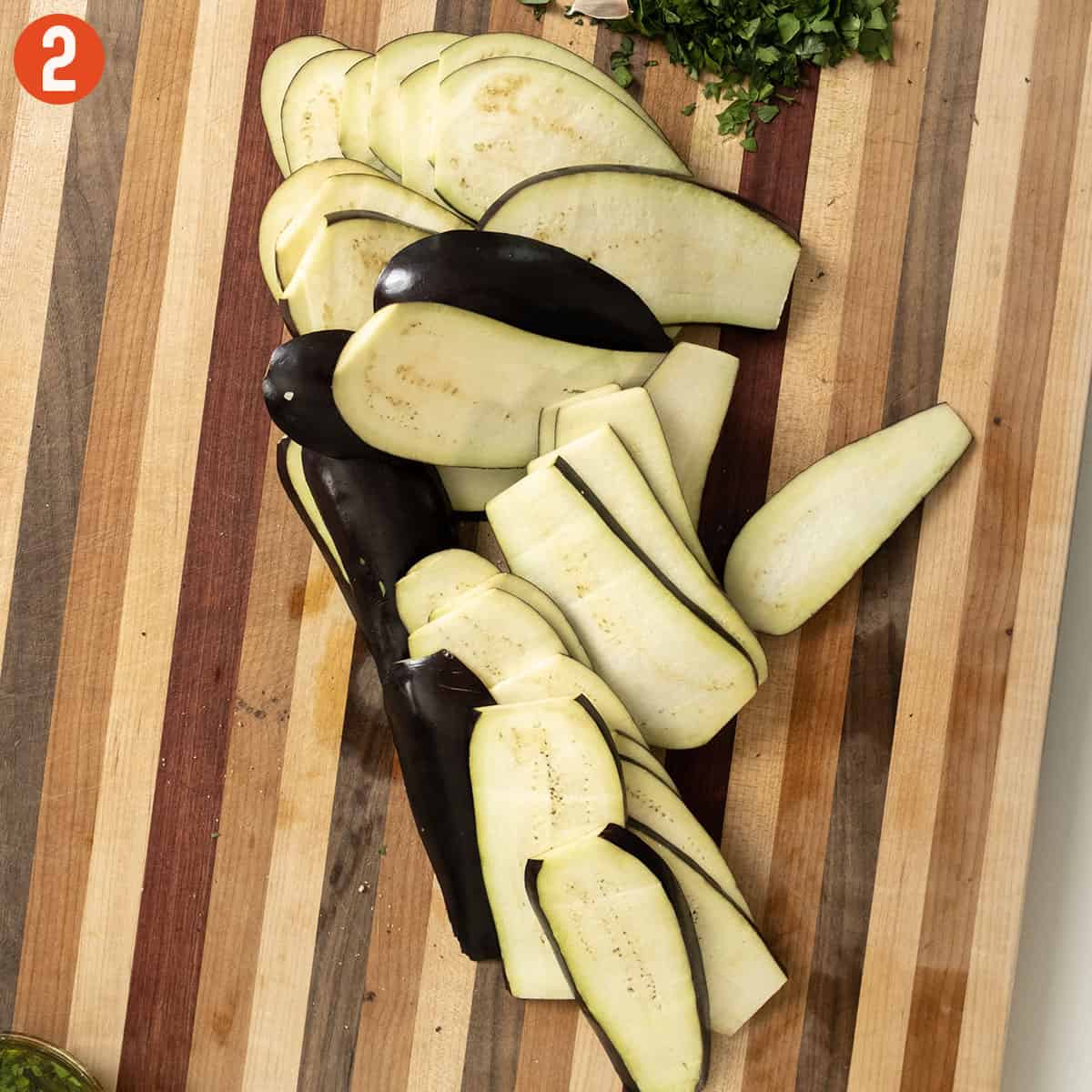 Eggplant sliced lengthwise on a cutting board.