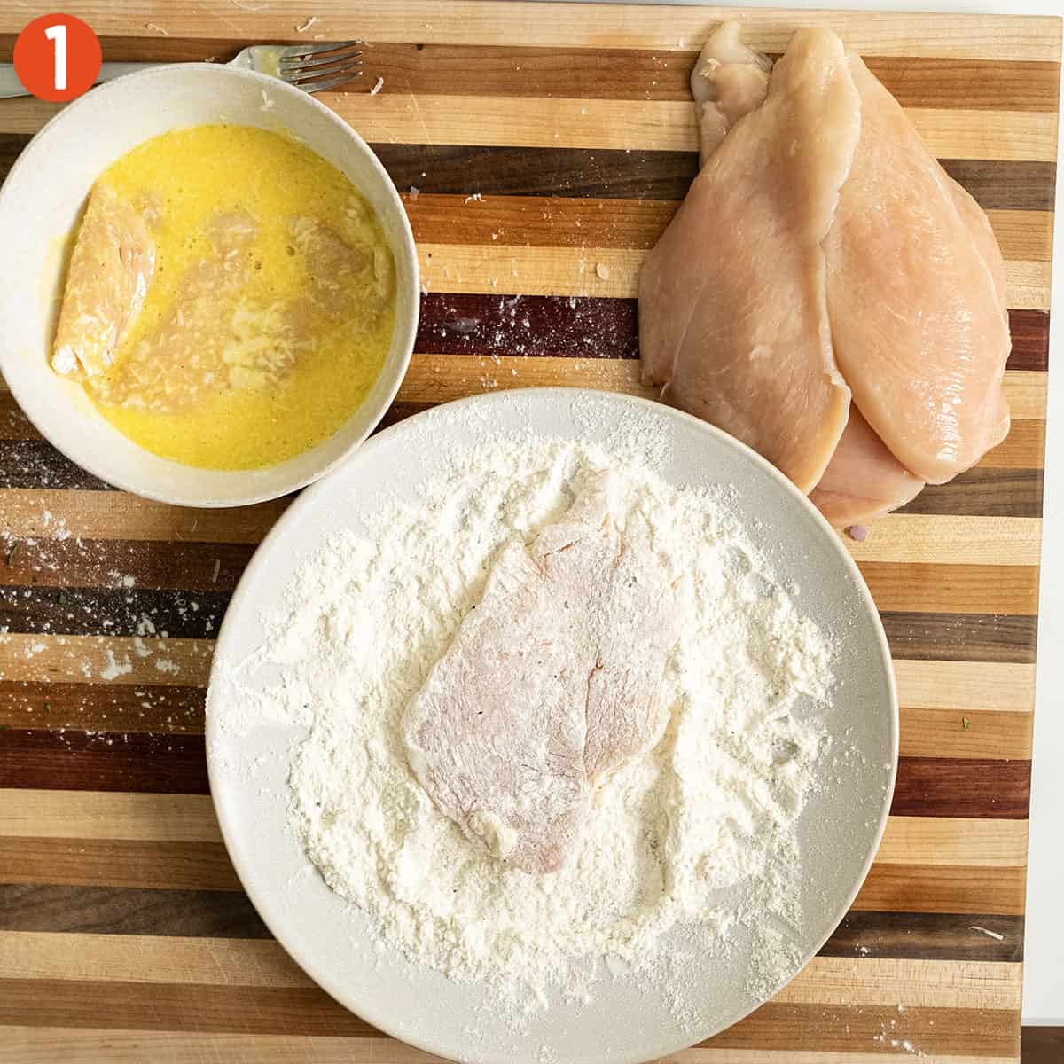 Dredging chicken breast in flour and dipping in egg.