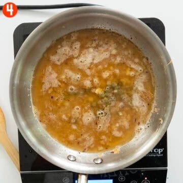 Simmering lemon sauce with chicken broth, white wine, capers, shallots, and garlic.