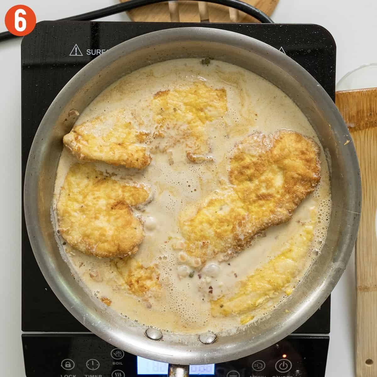 Simmering chicken breast in creamy lemon sauce.