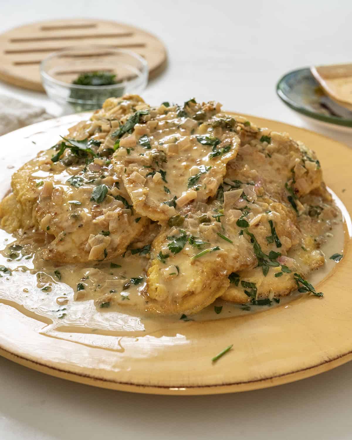 Chicken breast in creamy lemon sauce served on a plate and garnished with parsley.