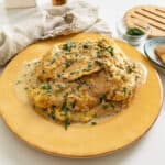 Chicken breast in creamy lemon sauce served on a plate and garnished with parsley.
