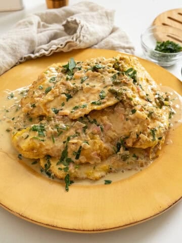 Chicken breast in creamy lemon sauce served on a plate and garnished with parsley.