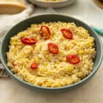 Creamy corn orzo in a bowl topped with red fresno peppers.
