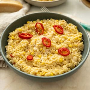 Creamy corn orzo in a bowl topped with red fresno peppers.