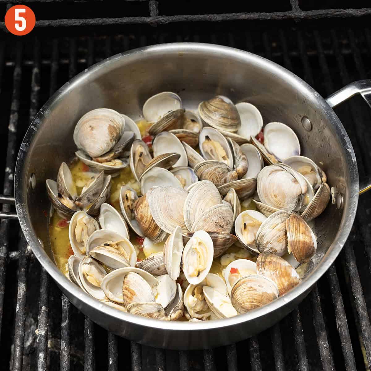 Grilled clams with white wine sauce in a saucepan on the grill.