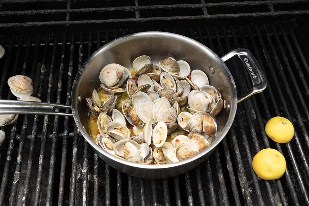 Grilled clams with white wine sauce in a saucepan on the grill.