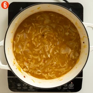 Onions and broth simmering in a dutch oven.