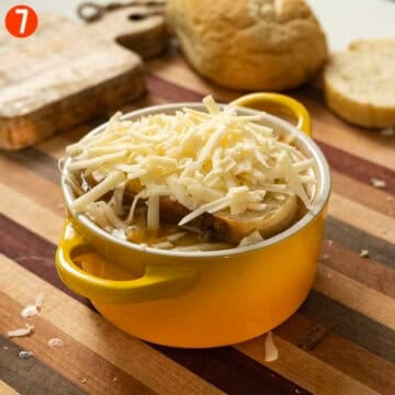 The italian onion soup in an oven safe bowl with bread and cheese on top.