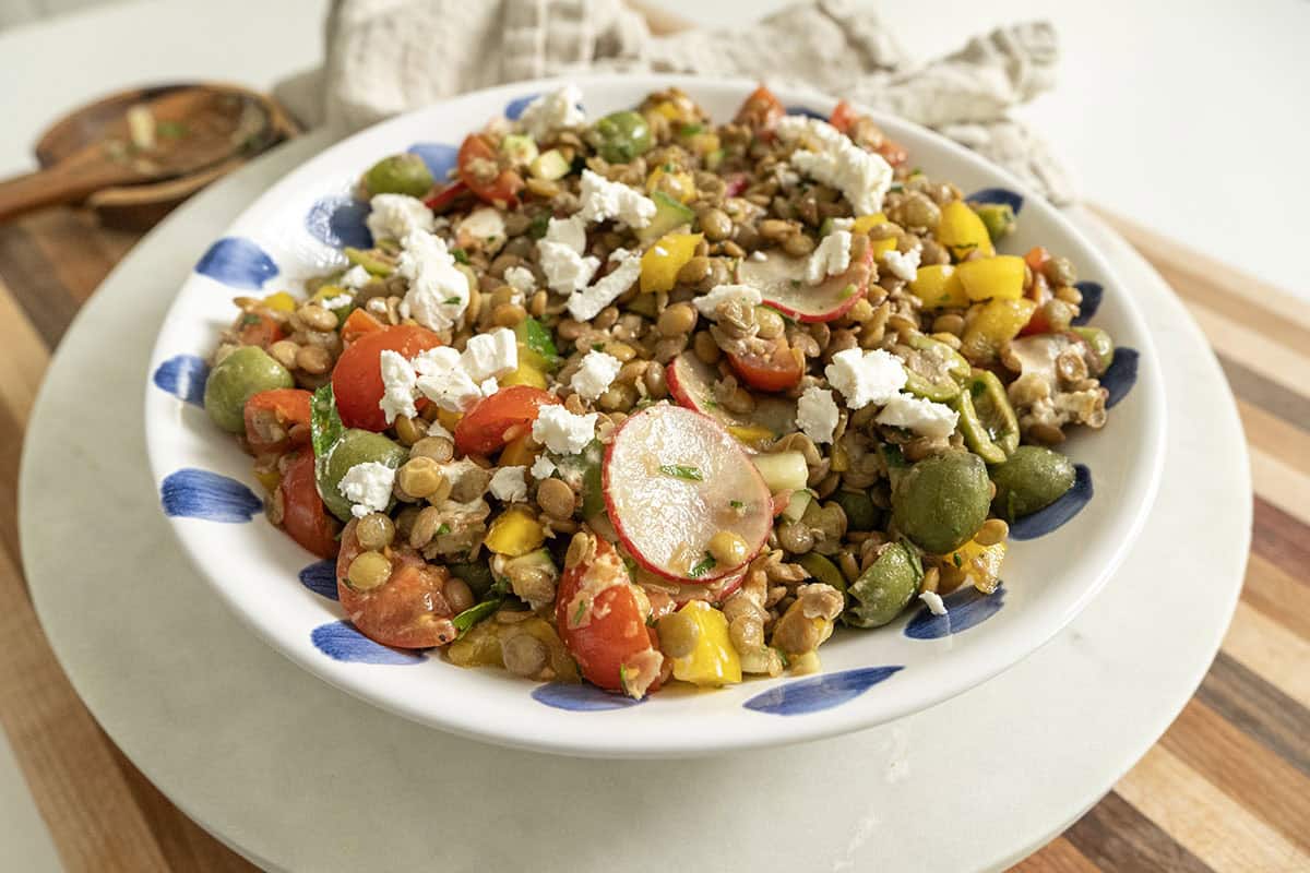 A cold Mediterranean lentil salad topped with goat cheese in a bowl. 