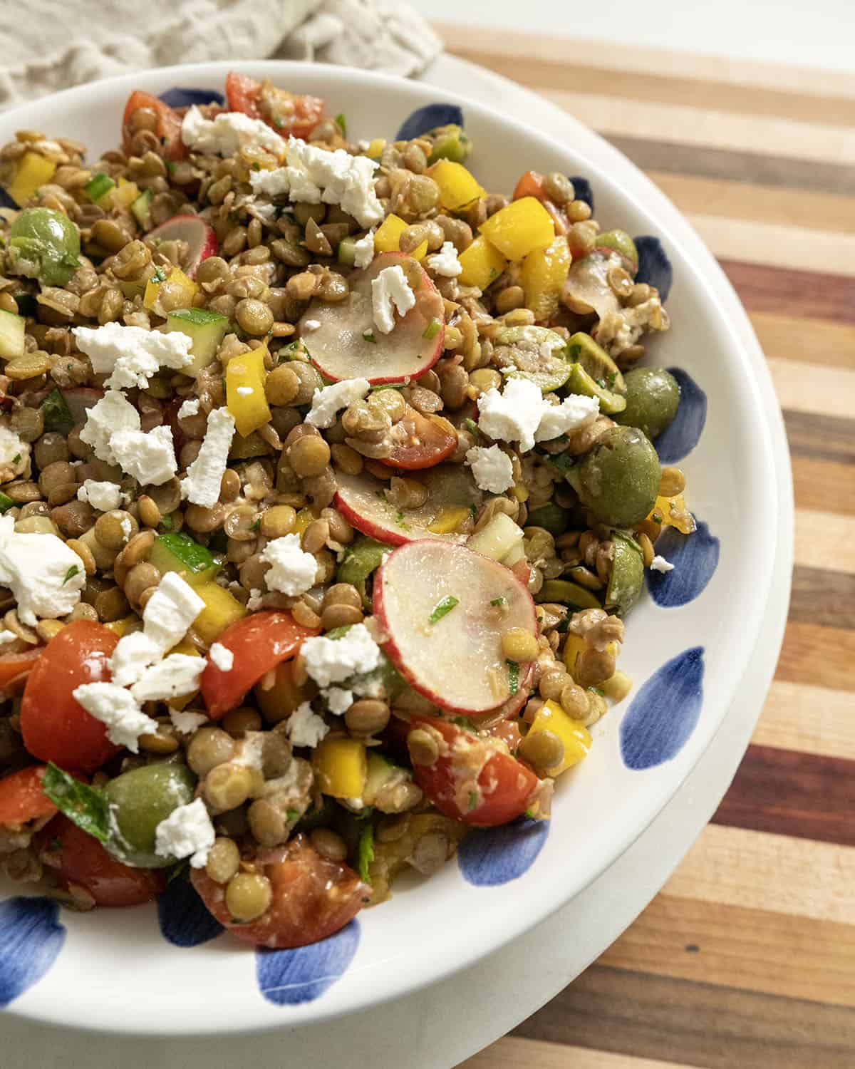A cold Mediterranean lentil salad topped with goat cheese in a bowl.