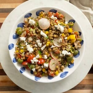 A cold Mediterranean lentil salad topped with goat cheese in a bowl.