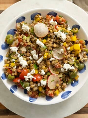 A cold Mediterranean lentil salad topped with goat cheese in a bowl.