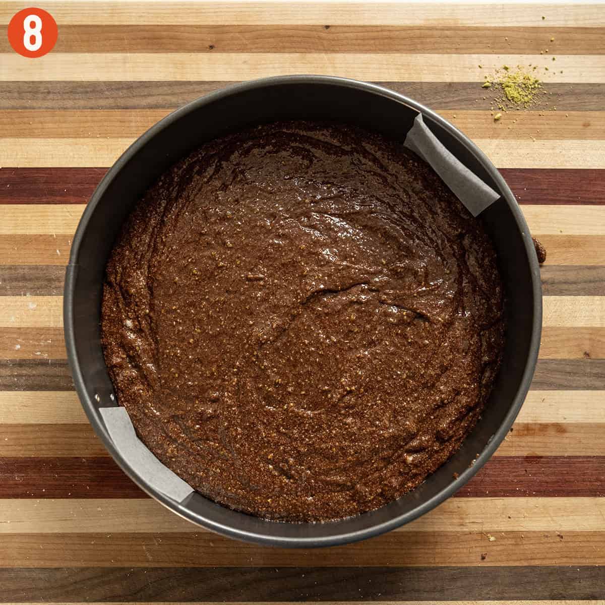 Placing batter in a parchment lined spring form pan.