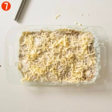 Pressing the potato mixture into a baking dish and topping with cheese.