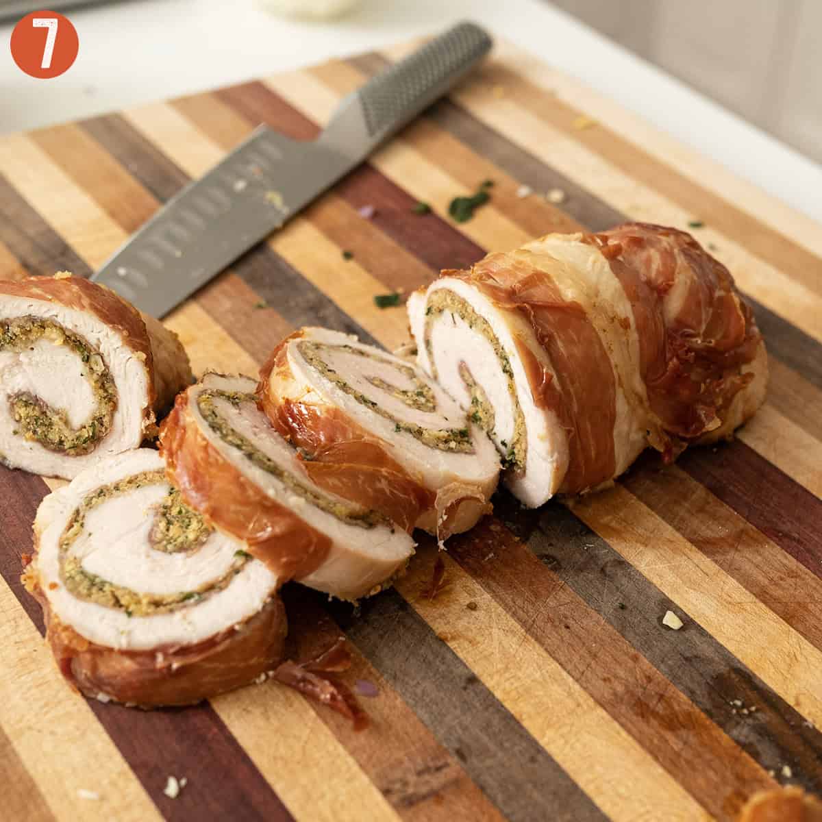 Slicing rolled stuffed turkey breast on a cutting board.