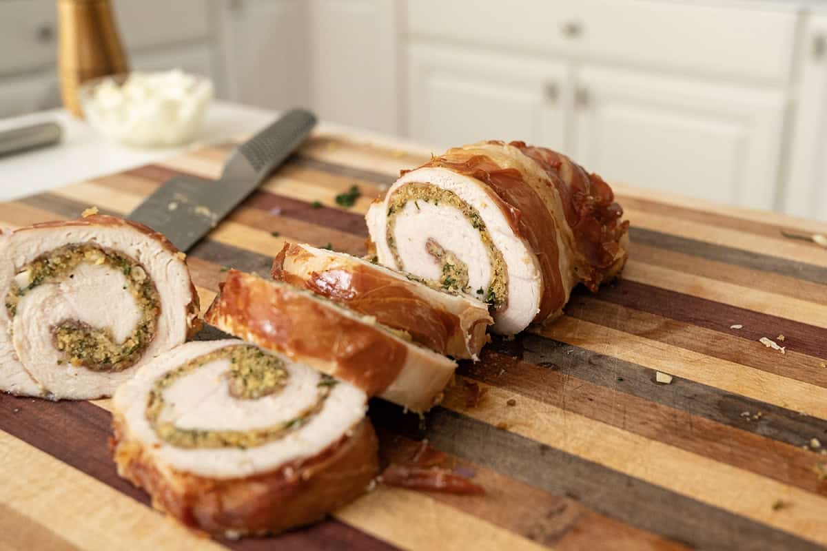 Rolled stuffed turkey breast sliced on a cutting board.