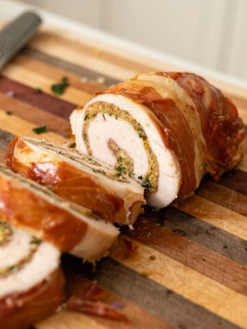 Rolled stuffed turkey breast sliced on a cutting board.