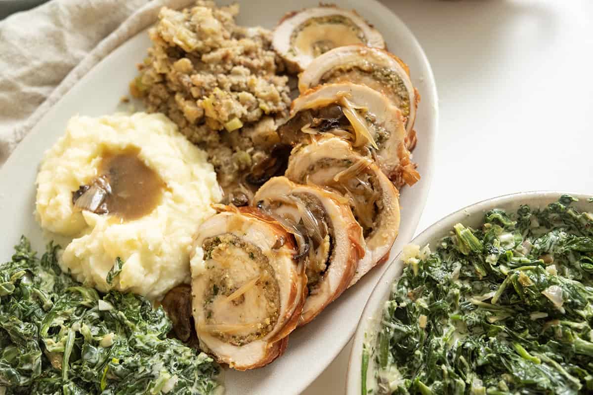 Sliced stuffed turkey breast on plate with sides.