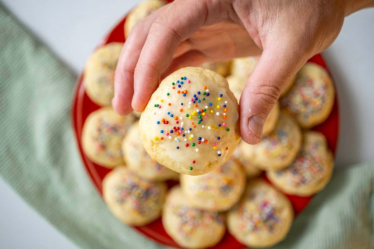 Holding a lemon ricotta cookie over the plate.